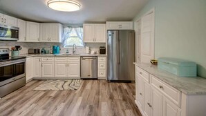 Una cocina moderna con armarios blancos, electrodomésticos de acero inoxidable y encimera de mármol.