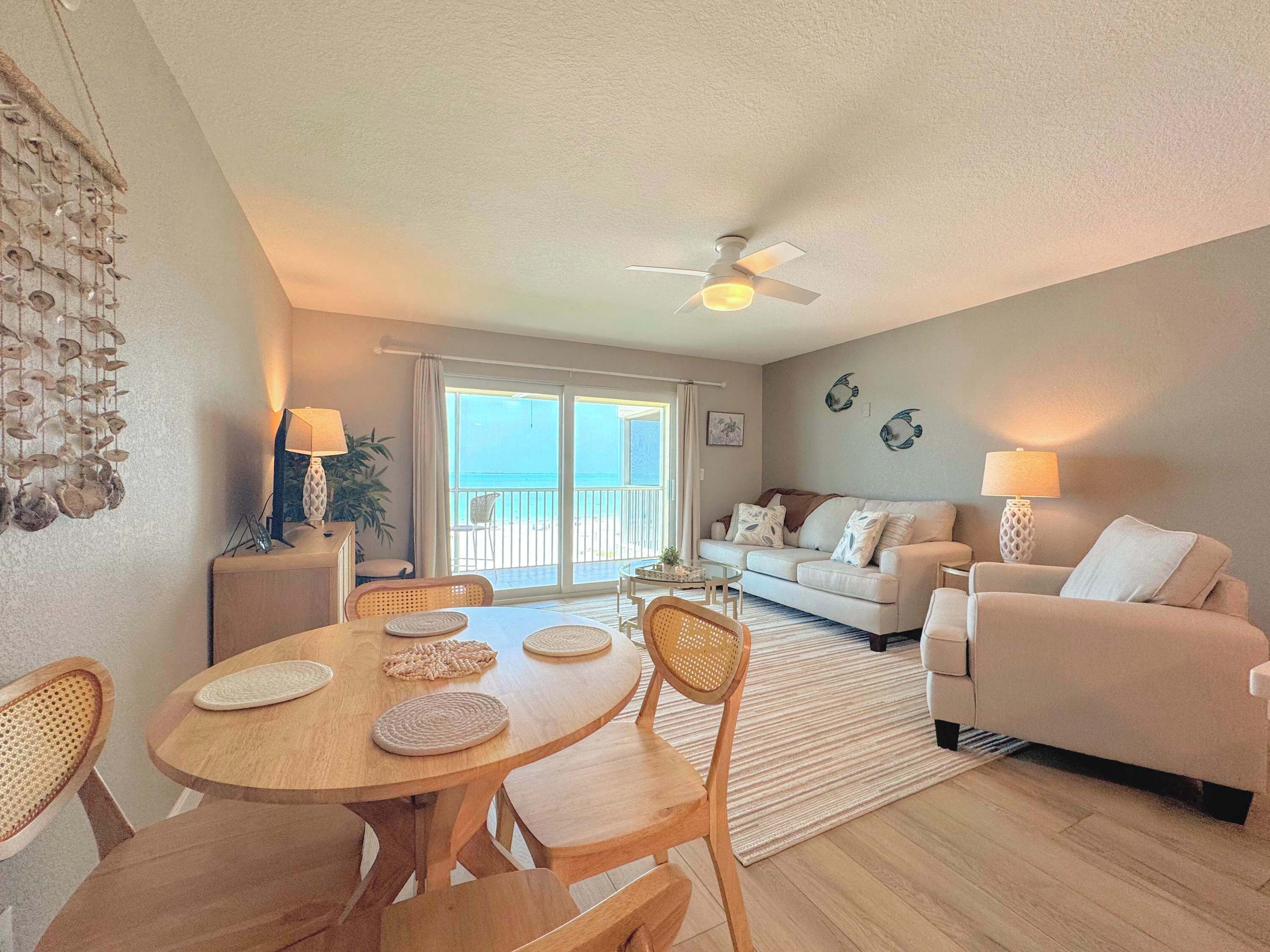 A living room with a dining table, chairs, a sofa, and a ceiling fan.