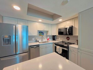 A modern kitchen with stainless steel appliances, white cabinetry, and a central island.