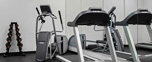 Ein Fitnessraum mit Laufbändern, Crosstrainern und einer Sammlung von Kurzhanteln.