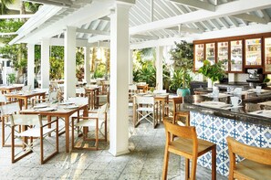 En restaurang med uteservering, vita pelare och en bardisk med kakelbeklädd yta.