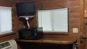 A wooden cabin interior with a microwave, a television on a stand, and a fire extinguisher. - Sun Outdoors Sarasota (Sarasota)