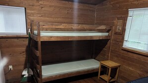A bunk bed in a wooden cabin room with a small table and a window. - Sun Outdoors Sarasota (Sarasota)