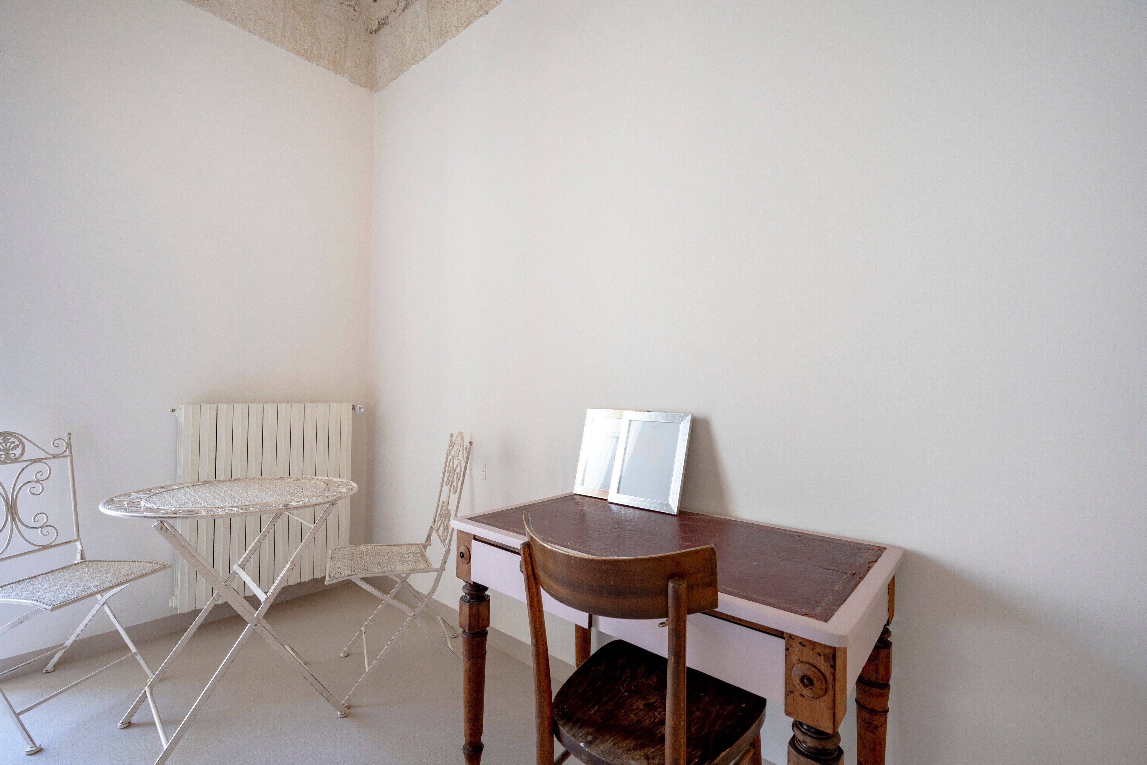 A corner room with a small table, a chair, and a radiator.