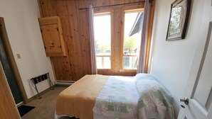 Une pièce avec un lit, des murs en bois, une fenêtre et une porte.