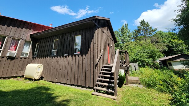 Une cabane en bois avec une porte rouge, un escalier et un petit porche.