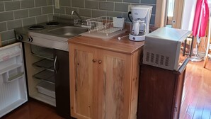 Une cuisine compacte équipée d’un réfrigérateur, d’une cuisinière, d’un évier et d’une machine à café.