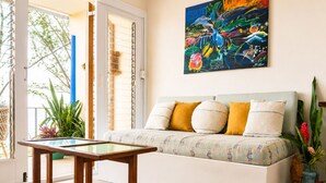 A cozy living room with a sofa, a coffee table, and a bookshelf. - Cliffside Caribbean Condo: Beach & Ocean Views (Ocho Rios)