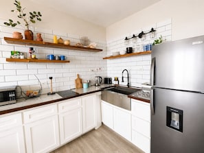 A modern kitchen with white cabinetry, a stainless steel refrigerator, and a variety of kitchen appliances.