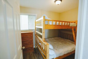 A bunk bed room with a wooden dresser and a window with blinds. - Heron Cottage - 3-Bedroom Cottage – Family Friendly (Trent Lakes)