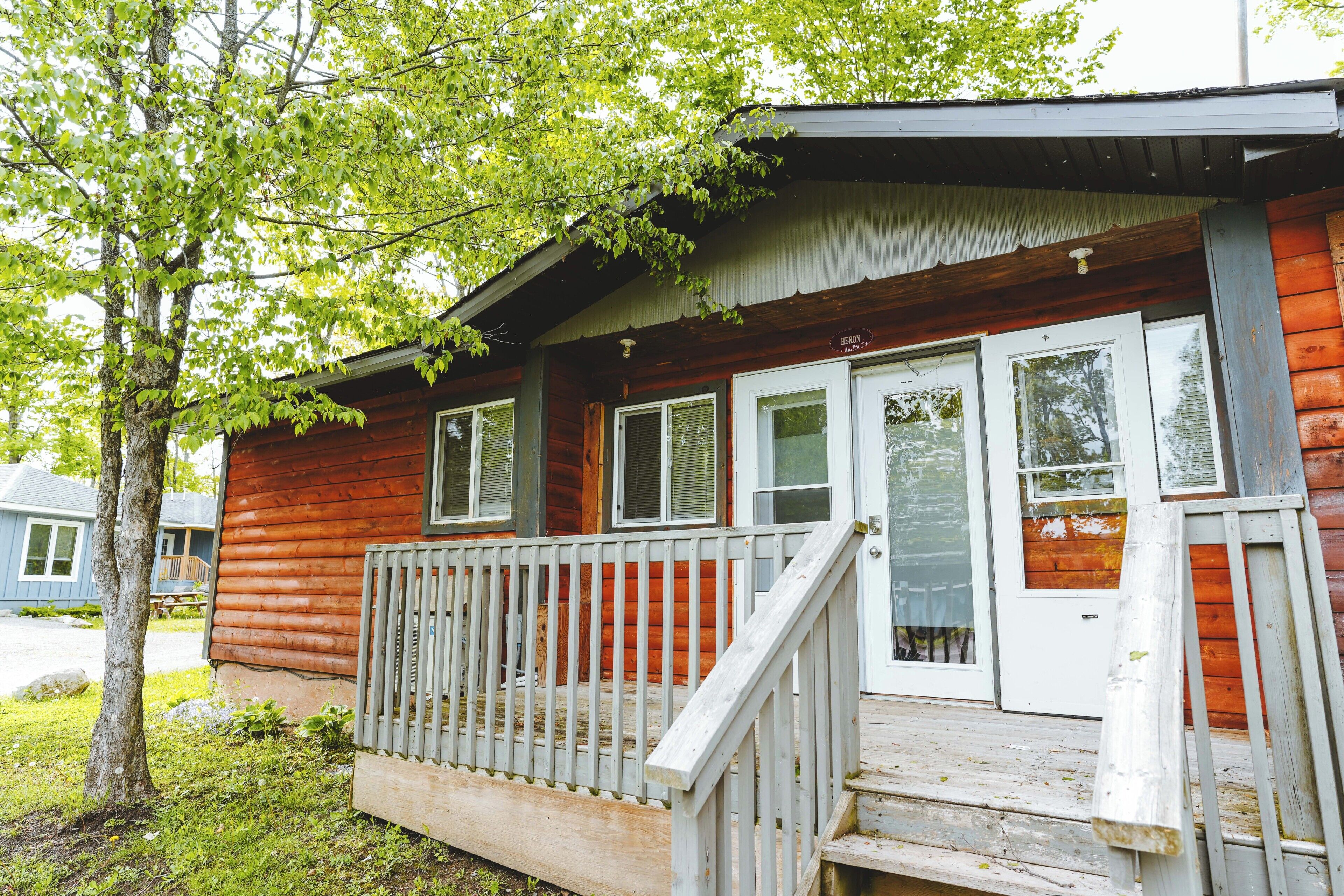 A wooden cabin with a porch, a set of stairs, and a door with a window.