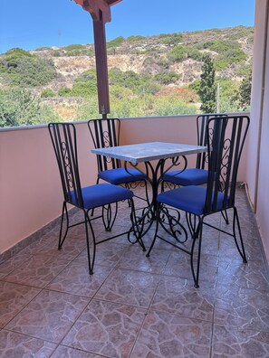 A balcony with a table and chairs, a tiled floor, and a view of a hilly landscape. - Family Olive Grove Retreat. (Petras)