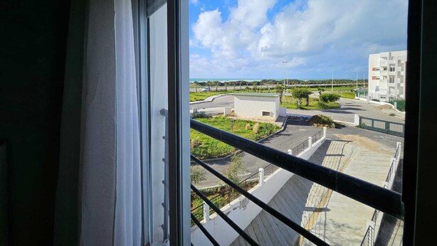 Blick aus einem Fenster auf ein Wohngebiet, mit blauem Himmel und vereinzelten Wolken.