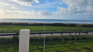Eine Küstenlandschaft mit einer grünen Wiese, einer Straße und einem Strand in der Ferne.