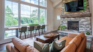 A spacious living room with a stone fireplace, large windows, and a comfortable seating area.