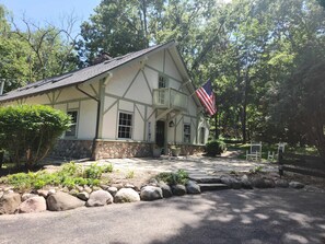 A traditional building with a stone foundation, a welcoming sign, and an American flag. - Tranquil Manor - Lake Geneva English Tudor Estate (Lake Geneva)