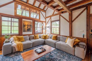 A cozy living room with a large sectional sofa, a wooden coffee table, and a patterned rug. - Tranquil Manor - Lake Geneva English Tudor Estate (Lake Geneva)