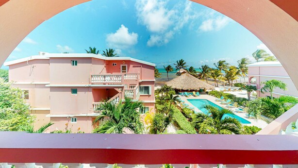 Um resort com piscina, palmeiras e céu claro.