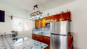 Uma cozinha com armários de madeira, geladeira de aço inoxidável e painel de azulejos estampados.