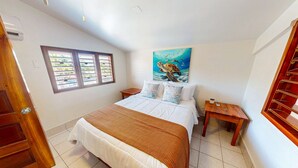 Um quarto com cama, um quadro, uma janela e uma porta de madeira.