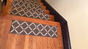 A staircase with wooden steps and patterned doormats.