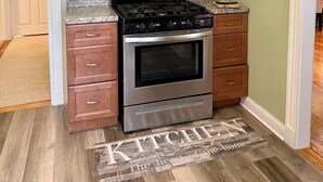 A kitchen with wooden cabinets, a stainless steel microwave, a gas stove, and an oven.