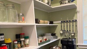 A kitchen with white shelves, a coffee maker, and various kitchen utensils.