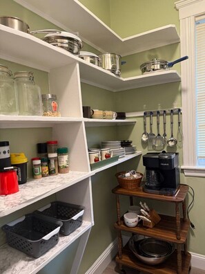 A kitchen with white shelves, a coffee maker, and various kitchen utensils.