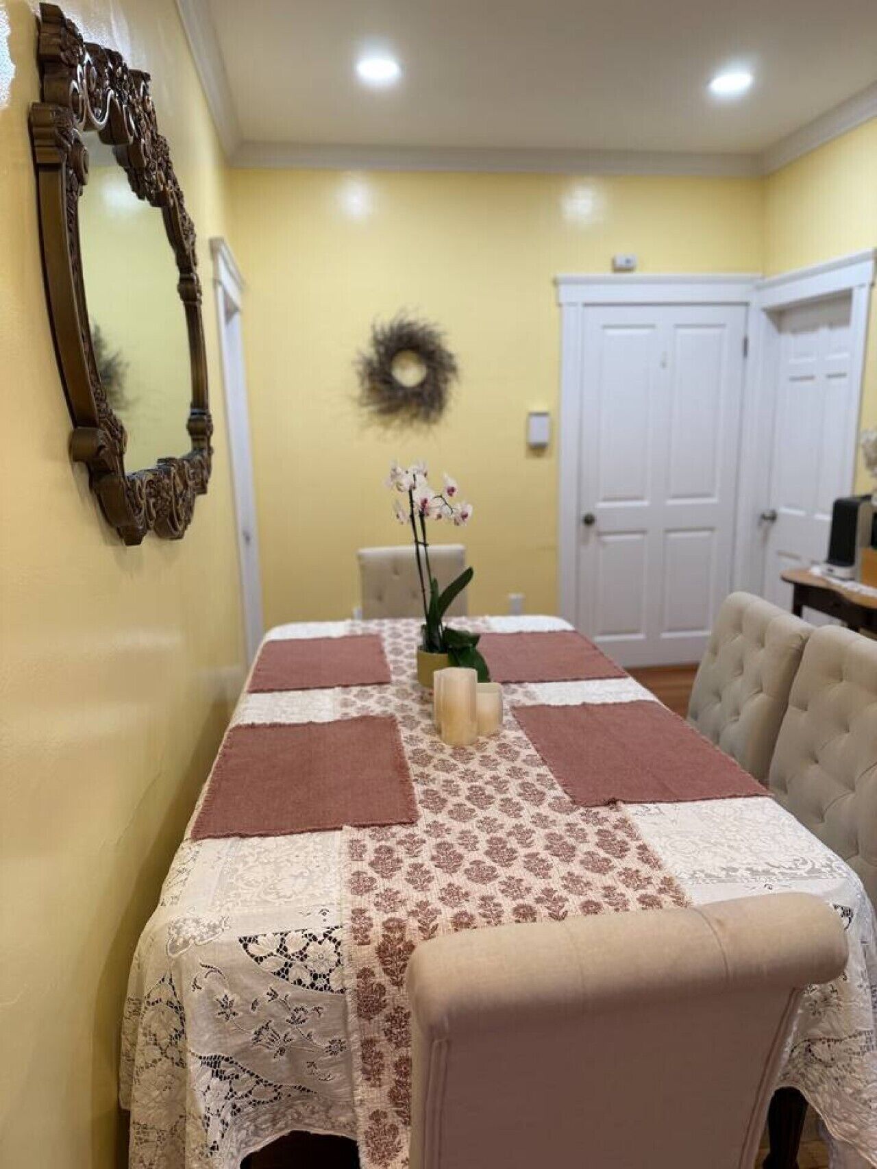 A dining area with a table set for four, a mirror, and a wall decoration.