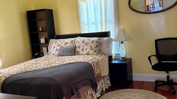 A bedroom with a bed, bedside table, chair, and a ceiling fan.