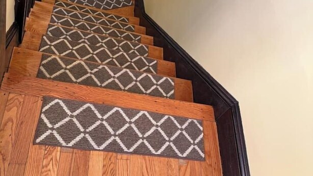 A staircase with wooden steps and patterned rugs.