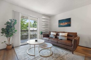 Ein Wohnzimmer mit braunem Ledersofa, einem runden Couchtisch, einem Blumentopf und einem Stadtbild an der Wand.