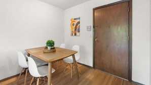 A room with a wooden table, white chairs, a potted plant, and a door. - UW Hospital Retreat with Dedicated Workspace (Madison)