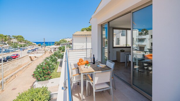 Een balkon met een tafel, stoelen en uitzicht op zee.