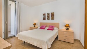 Een slaapkamer met een bed, twee nachtkastjes, een houten hoofdeinde en drie wanddecoraties.