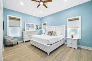 Un dormitorio con una cama grande, muebles blancos y un ventilador de techo.