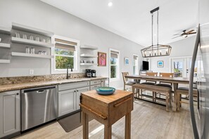 Eine moderne Küche mit Edelstahlgeräten, Holzschränken und einem Essbereich mit Holztisch und Stühlen.
