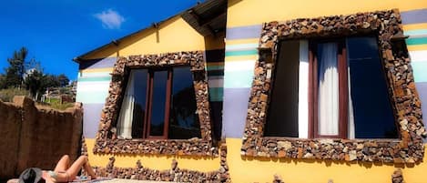 A yellow building with stone-framed windows and a person lying on a towel outside.