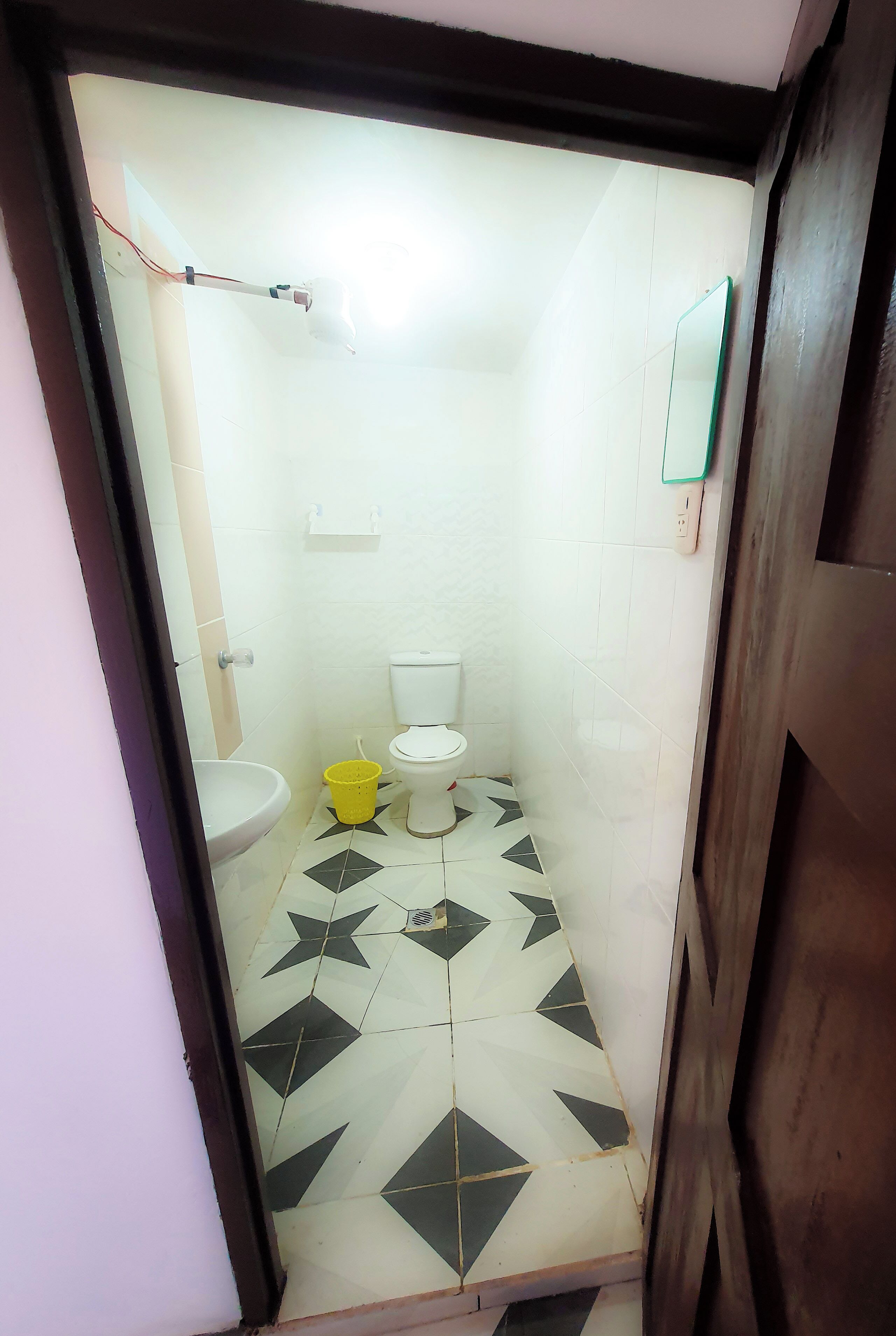 Un bany petit amb un vàter, un lavabo i un paperer groc.