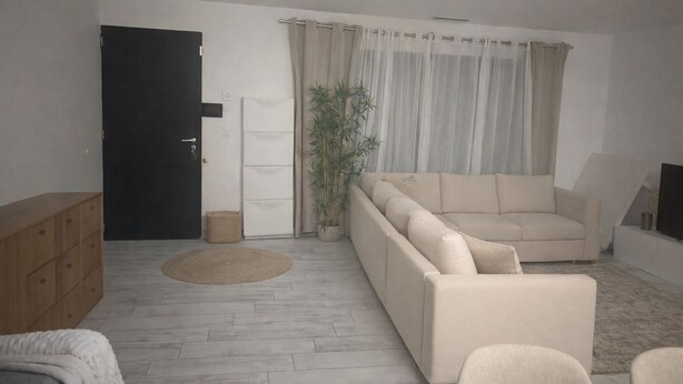 A living room with a sofa, a wooden cabinet, a plant, and a television. - Modern villa with a large private above-ground pool – 3 bedrooms (Vacqueyras)
