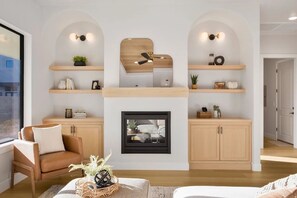 Ein Wohnzimmer mit Kamin, Holzregalen, Deckenventilator und Sofa.
