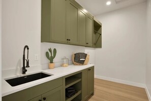 A kitchen with a black sink, green cabinets, a white countertop, and a cactus plant. - Fully Furnished Modern Desert Retreat in Hurricane (Hurricane)