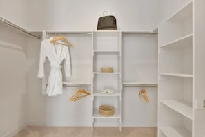 Un dressing avec des étagères blanches, une tringle à vêtements et un porte-chaussures.