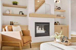 A living room with a sofa, a fireplace, wooden shelves, and a staircase. - Fully Furnished Modern Desert Retreat in Hurricane (Hurricane)