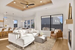 Ein modernes Wohnzimmer mit einem weißen Sofa, einem braunen Sessel und einem Kamin.