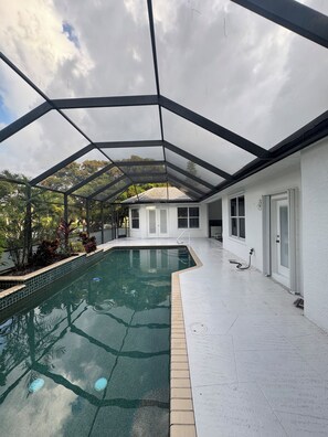 Ein überdachter Pool mit freiem Blick auf die Umgebung, einschließlich eines Hauses und Vegetation.