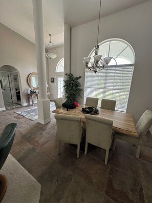 A dining area with a wooden table and chairs, a potted plant, and a chandelier. - Lovely 3-bedroom house with AC in charming Burnt store Marina (Punta Gorda)