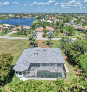 A residential property with a large swimming pool, surrounded by lush greenery and a view of a lake. - Lovely 3-bedroom house with AC in charming Burnt store Marina (Punta Gorda)