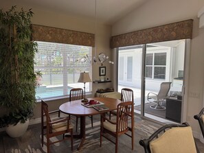 A dining area with a round table, chairs, a potted plant, and a view of the outdoors through large windows. - Lovely 3-bedroom house with AC in charming Burnt store Marina (Punta Gorda)