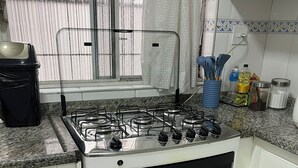 Una cocina con estufa a gas, horno y distintos utensilios de cocina sobre la encimera.